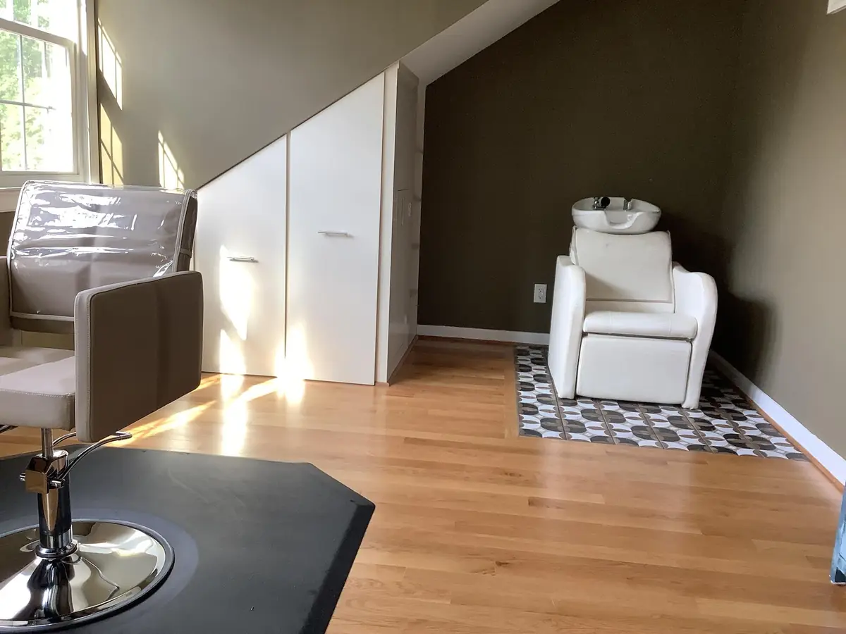 The upstairs rental room: wood floor, sloped ceiling, chair and shampoo sink.